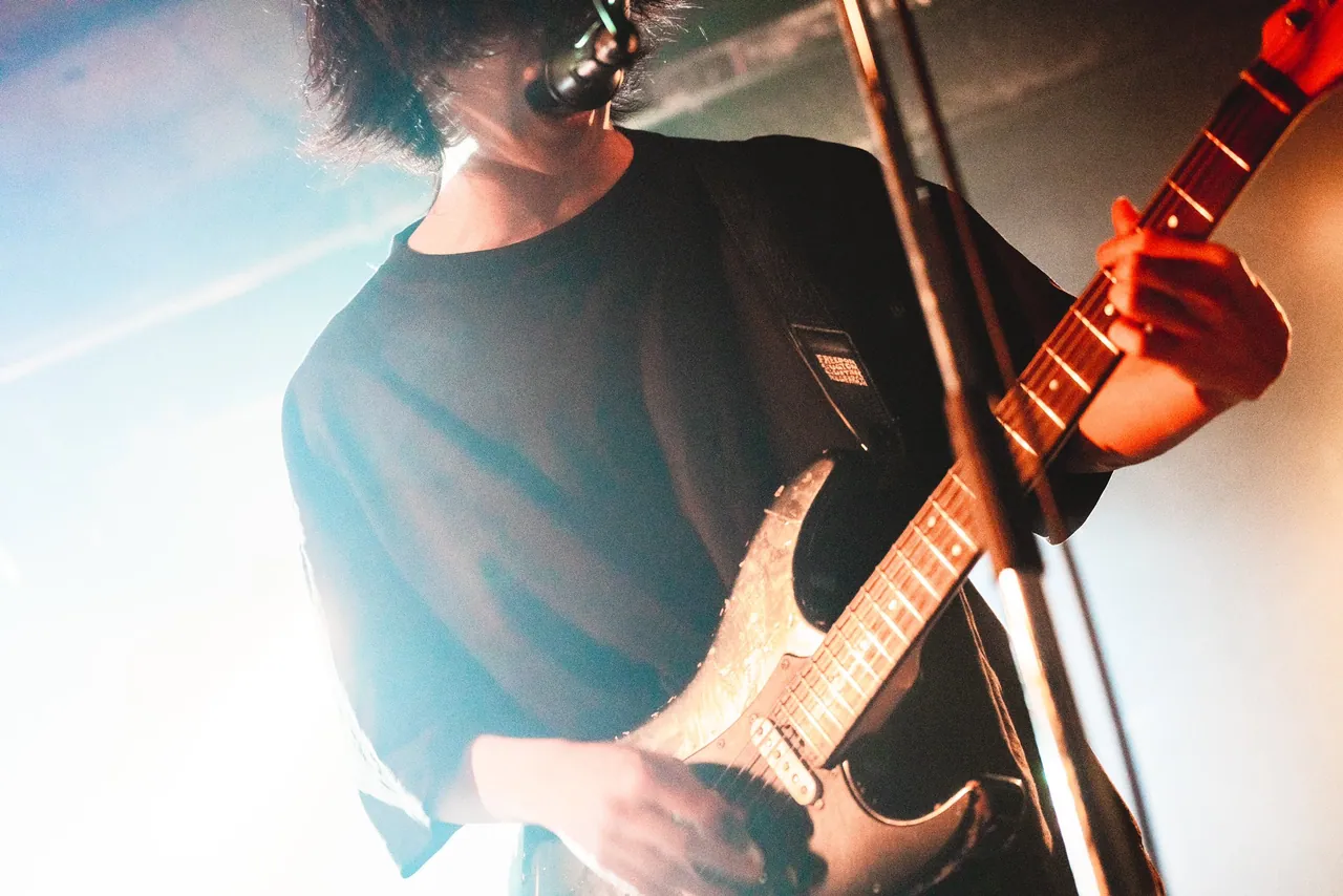 白いもやの中、低いアングルから見たギタリスト