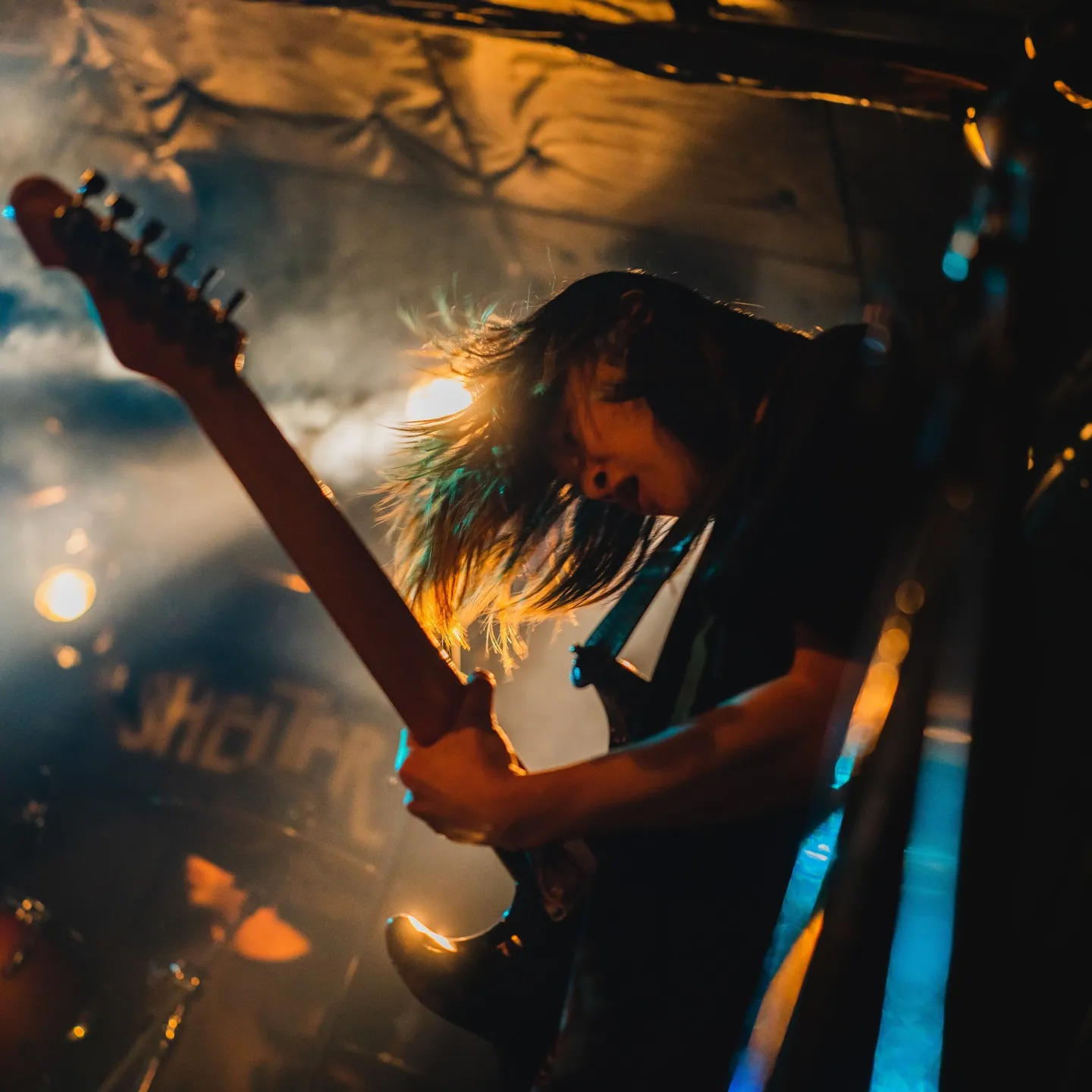 逆光の中でギターを振り上げるギタリスト